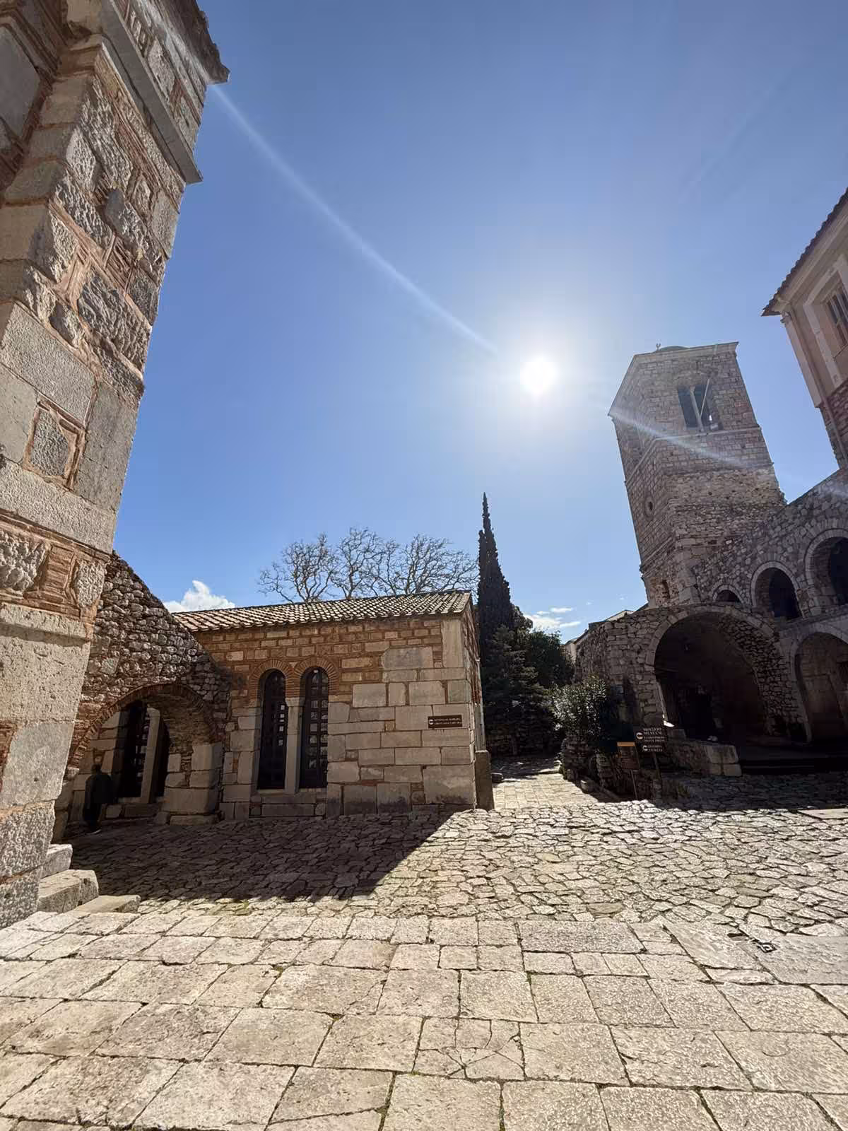 Sunlit courtyard and bell tower at Hosios Loukas Monastery, a highlight of Delphi and Arachova private tour