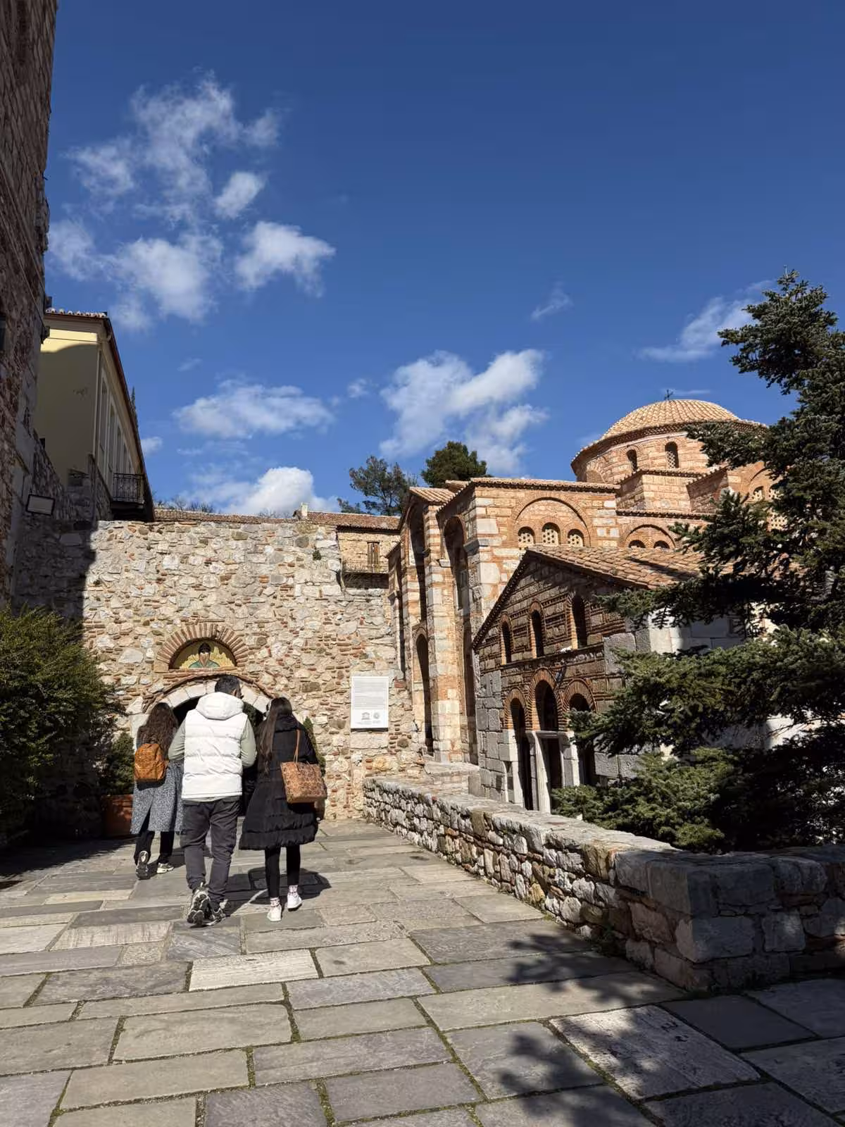 Visitors walking to Hosios Loukas Monastery church, part of a full-day private Delphi and Arachova village trip