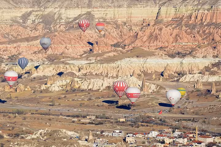 Hot air balloons floating over Cappadocia valleys and fairy chimneys at sunrise, Turkey balloon tour