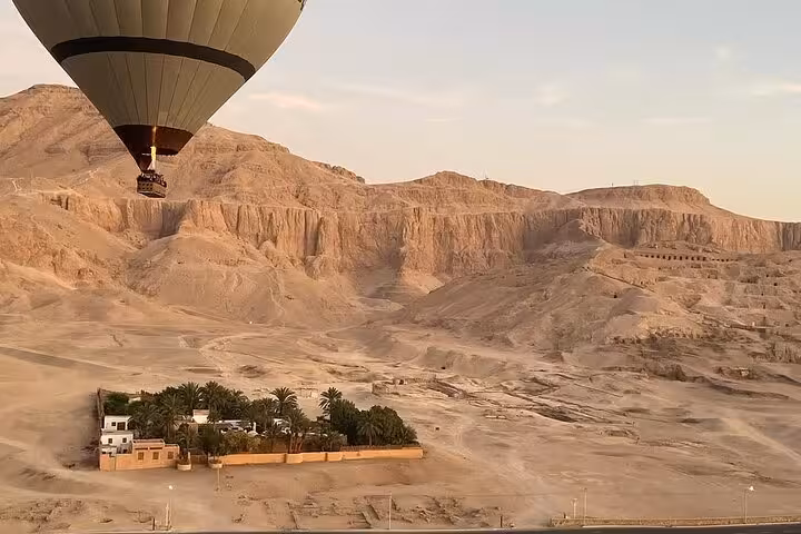 Hot air balloon over Luxor West Bank desert cliffs at sunrise, with hotel pickup and drop-off service