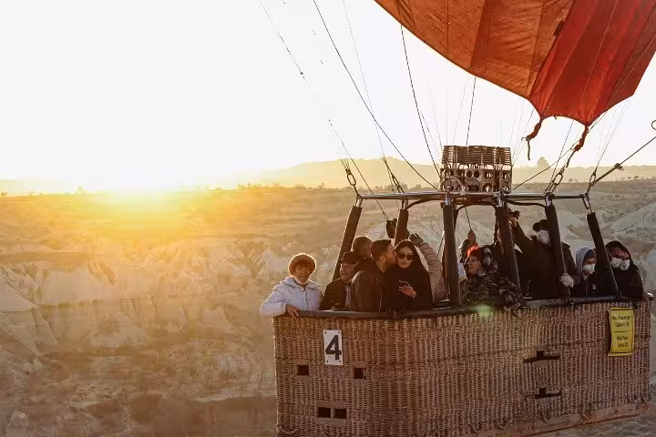 Passengers in wicker basket on sunrise hot air balloon ride, lifetime experience tour over scenic desert