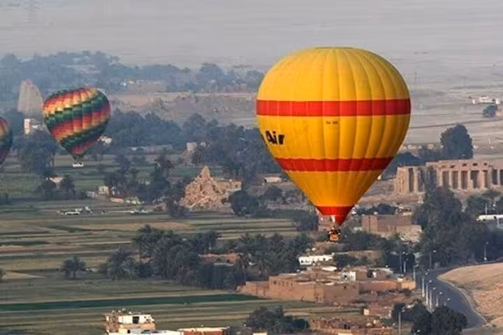 Hot air balloons drifting above Luxor farmlands on a 2-day historical tour from Sharm El Sheikh to Cairo and Luxor