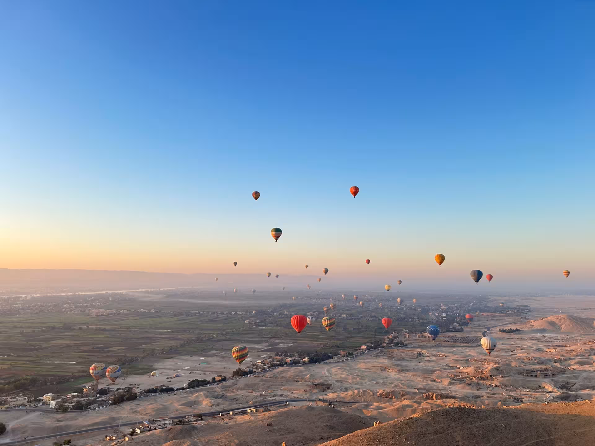 Colorful hot air balloons soar over the Valley of the Nile at sunrise, offering breathtaking aerial views.