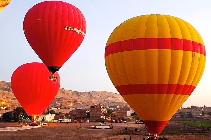 Colorful hot air balloons inflating at sunrise in Luxor, Egypt, with hotel pickup and drop-off tour