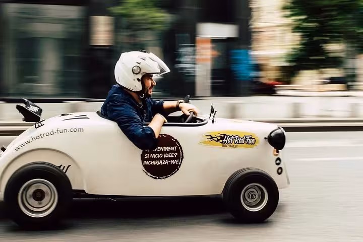 Man in white helmet driving a white Hot Rod Fun miniature car on Bucharest streets
