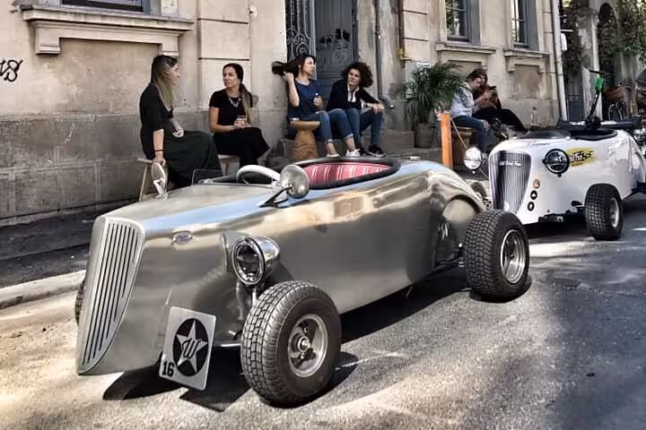 Shiny silver vintage hot rod car parked on Bucharest street with tourists sitting on steps nearby