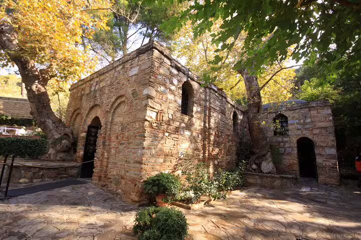 Exterior view of the House of Virgin Mary surrounded by trees, featured in Ephesus tour from Izmir.