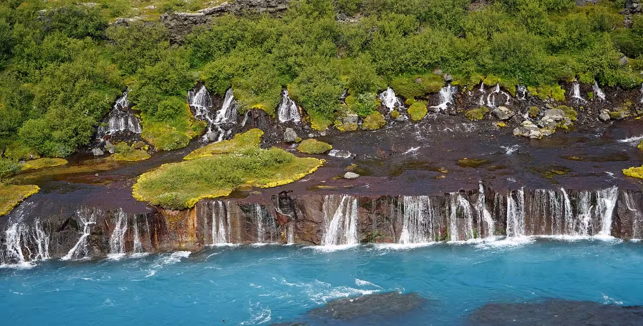 Hraunfossar waterfalls cascading over lava rocks into turquoise Hvítá river, West Iceland
