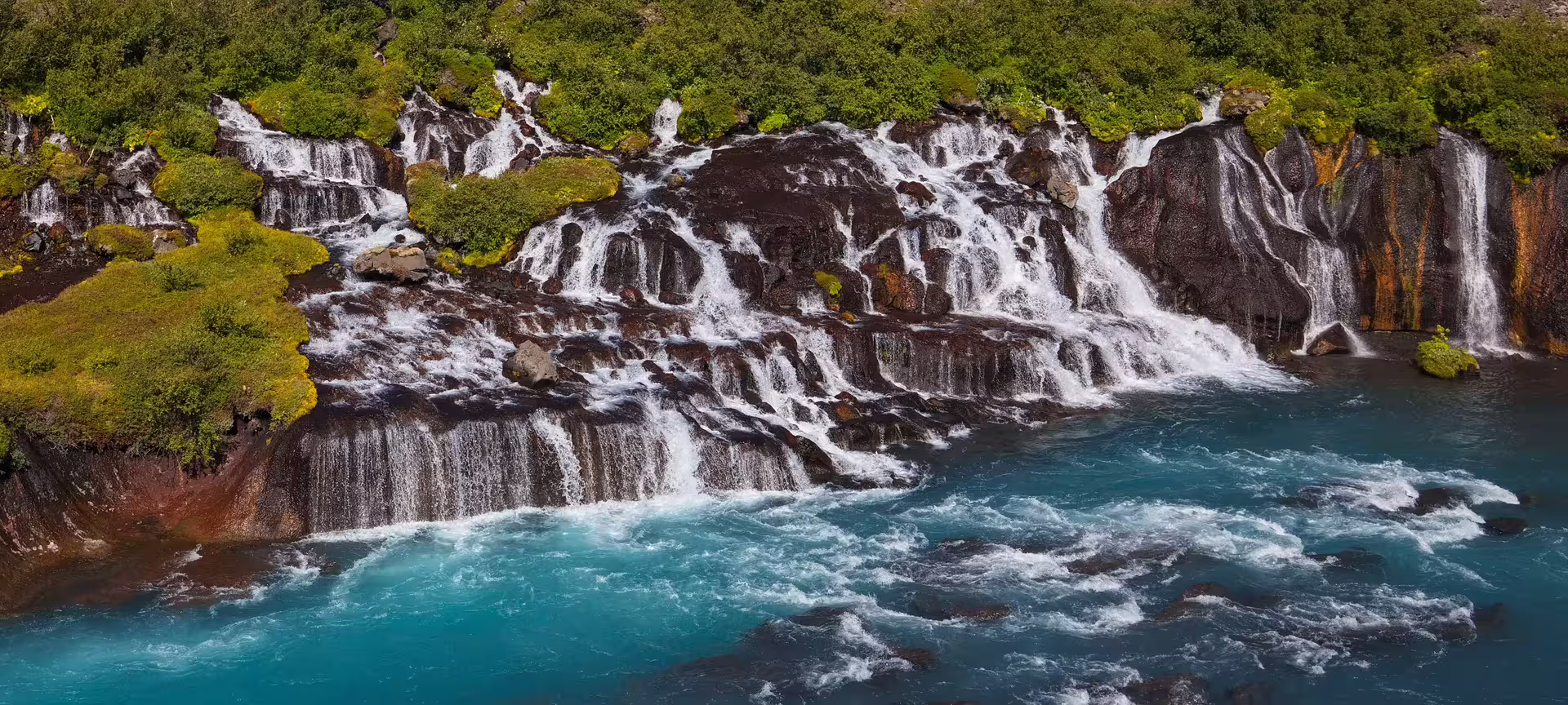 Enchanting Hraunfossar waterfalls cascading over ancient lava rock into glacial blue river on Iceland witchcraft magic tour