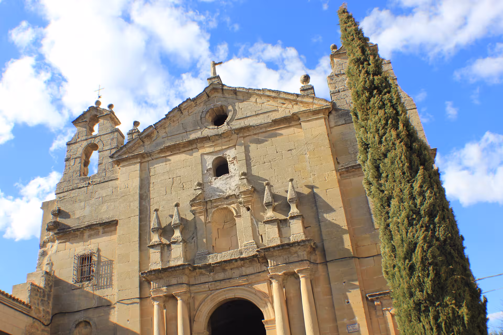 Baroque church facade and cypress tree in Huete, Cuenca, featured on the Guided tour of Huete Monumental