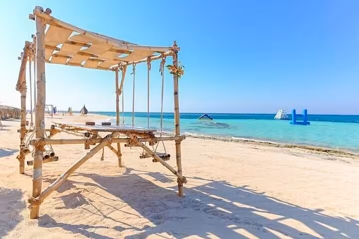 Wooden beach swing cabana on Hula Hula Island, Hurghada with turquoise Red Sea and floating water park