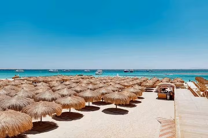 Hula Hula Island beach with straw umbrellas and turquoise Red Sea, ideal for lunch and water sports day trip