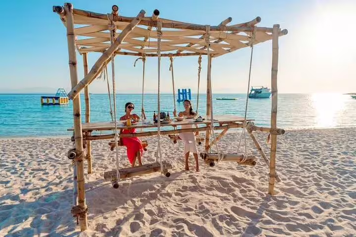 Guests relaxing on bamboo beach swing at Hula Hula Island, Hurghada VIP boat snorkeling tour on the Red Sea