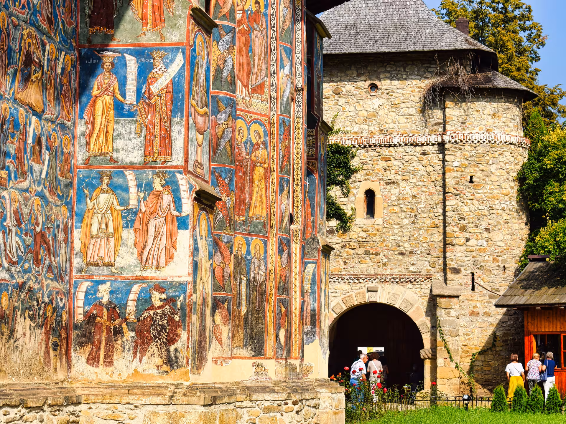 Colorful frescoes and stone tower at Humor Monastery on a 2-day Bucovina painted monasteries tour
