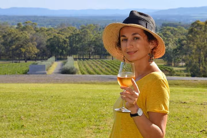 Woman enjoying a glass of wine at Hunter Valley Winery, overlooking lush vineyards, ideal for premium private tours.