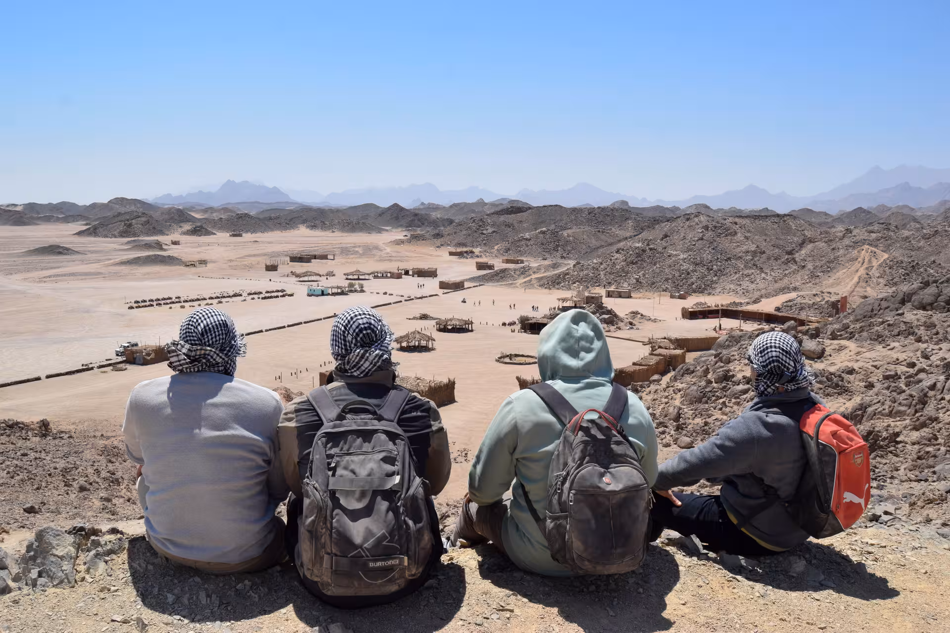 Travelers overlook Hurghada desert Bedouin village on ATV quad safari and camel ride tour in Egypt