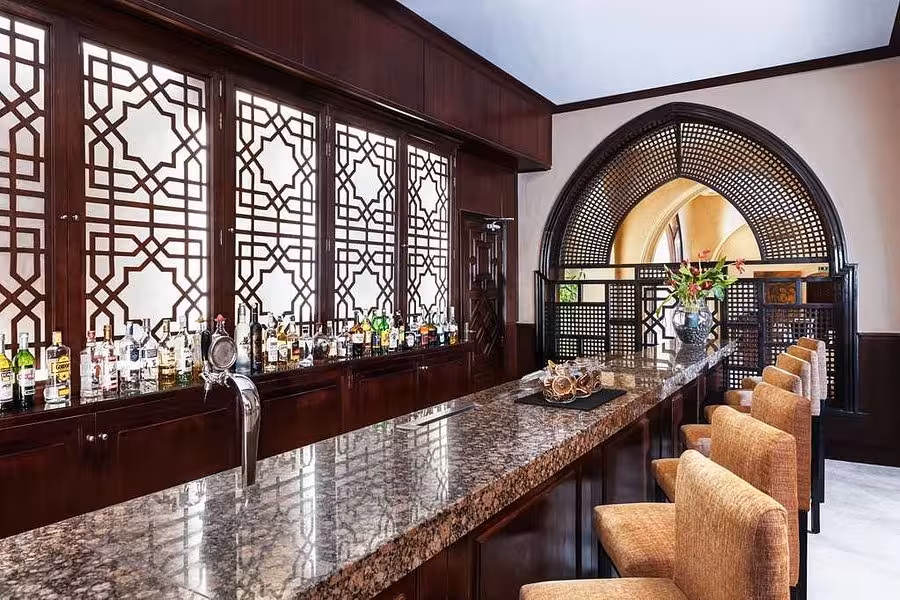 Chic bar interior in Hurghada with ornate woodwork, granite counter, and a variety of spirits for a sophisticated evening.