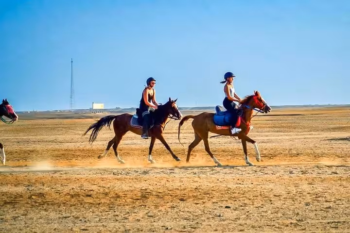 Two riders gallop across Hurghada desert toward the coast on one-hour beach horse riding tour with hotel transfer