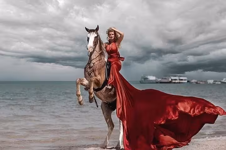 Rider in red dress on rearing horse by Hurghada beach, scenic Red Sea horse riding tour photo spot