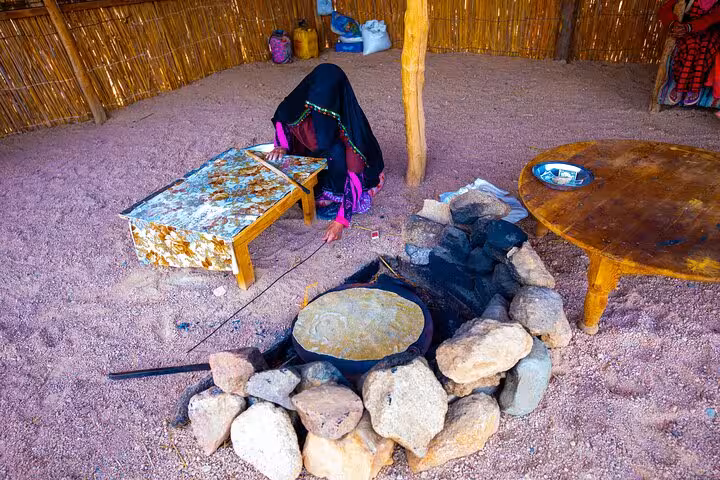Bedouin woman baking traditional bread at desert camp on Hurghada safari with ATV, buggy, camel ride and show