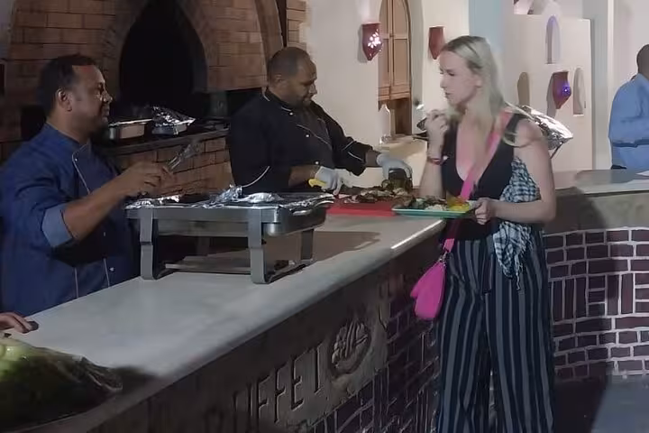 Tourist served hot buffet at Bedouin camp dinner during Hurghada ATV quad bike and buggy desert safari with show