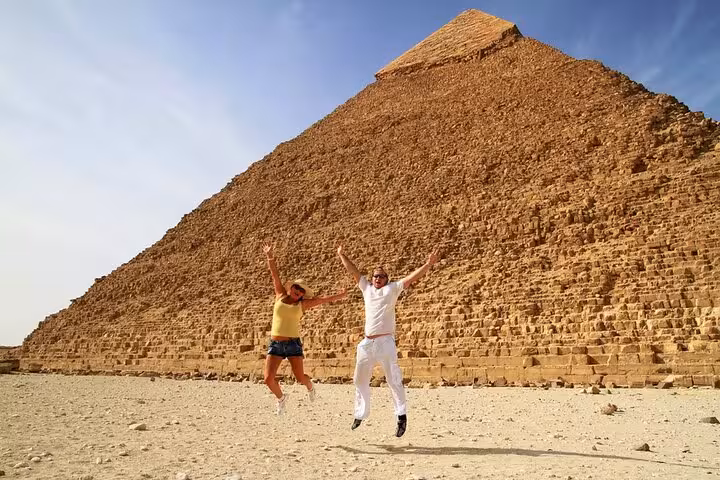First-time visitors jumping by the Great Pyramid of Giza on Hurghada to Cairo pyramids and museum tour