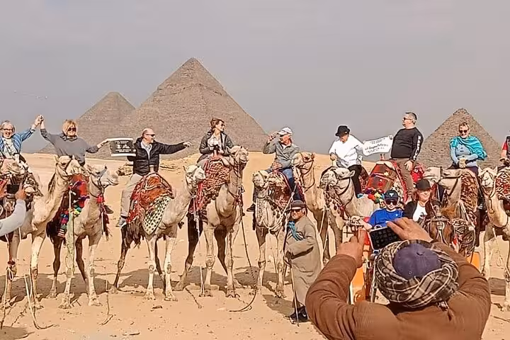 Tourists on camel ride in front of the Giza Pyramids during full-day Hurghada to Cairo pyramids tour