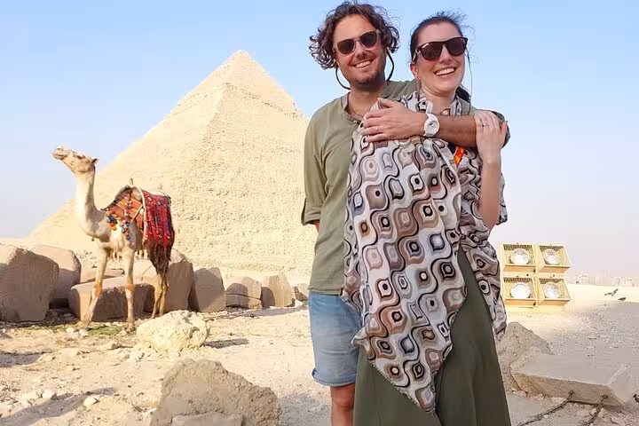 Happy couple at Giza Pyramids with camel nearby on Hurghada to Cairo private tour and Grand Museum visit