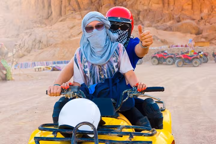 Couple riding yellow ATV quad bike in Hurghada desert, guided tour with BBQ dinner, helmets and hotel transfer