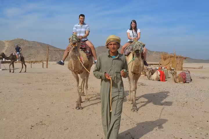 Tourists on camel ride in Hurghada desert camp, part of quad bike ATV safari with BBQ dinner and transfer