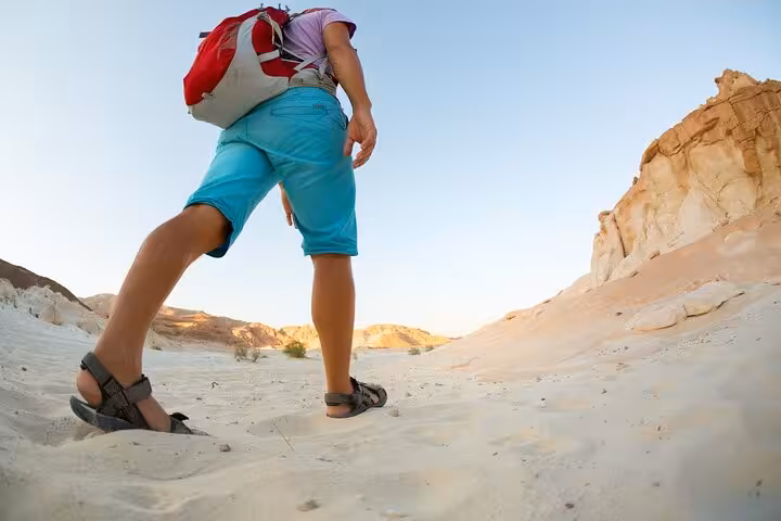 Traveler hiking sandy canyon in Hurghada desert before Jeep stargazing safari and Bedouin dinner experience