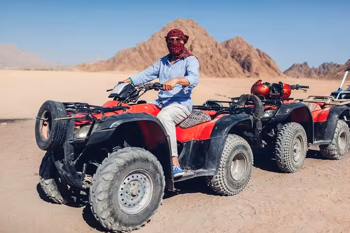 Hurghada desert quad biking adventure with ATVs lined up near mountains, off-road safari tour with BBQ and transfer