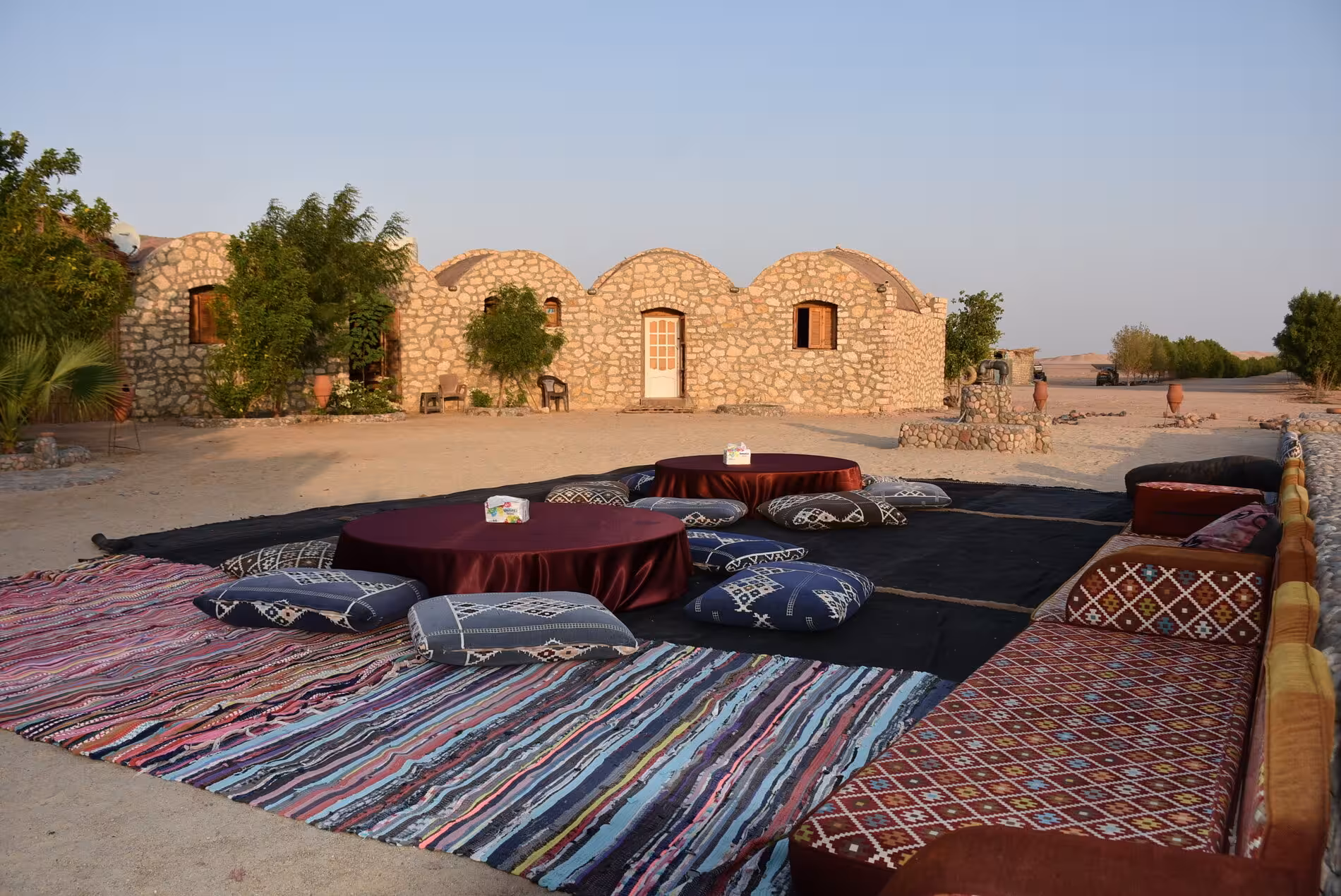 Traditional Bedouin seating area with floor cushions and low tables at a desert stone lodge in Hurghada