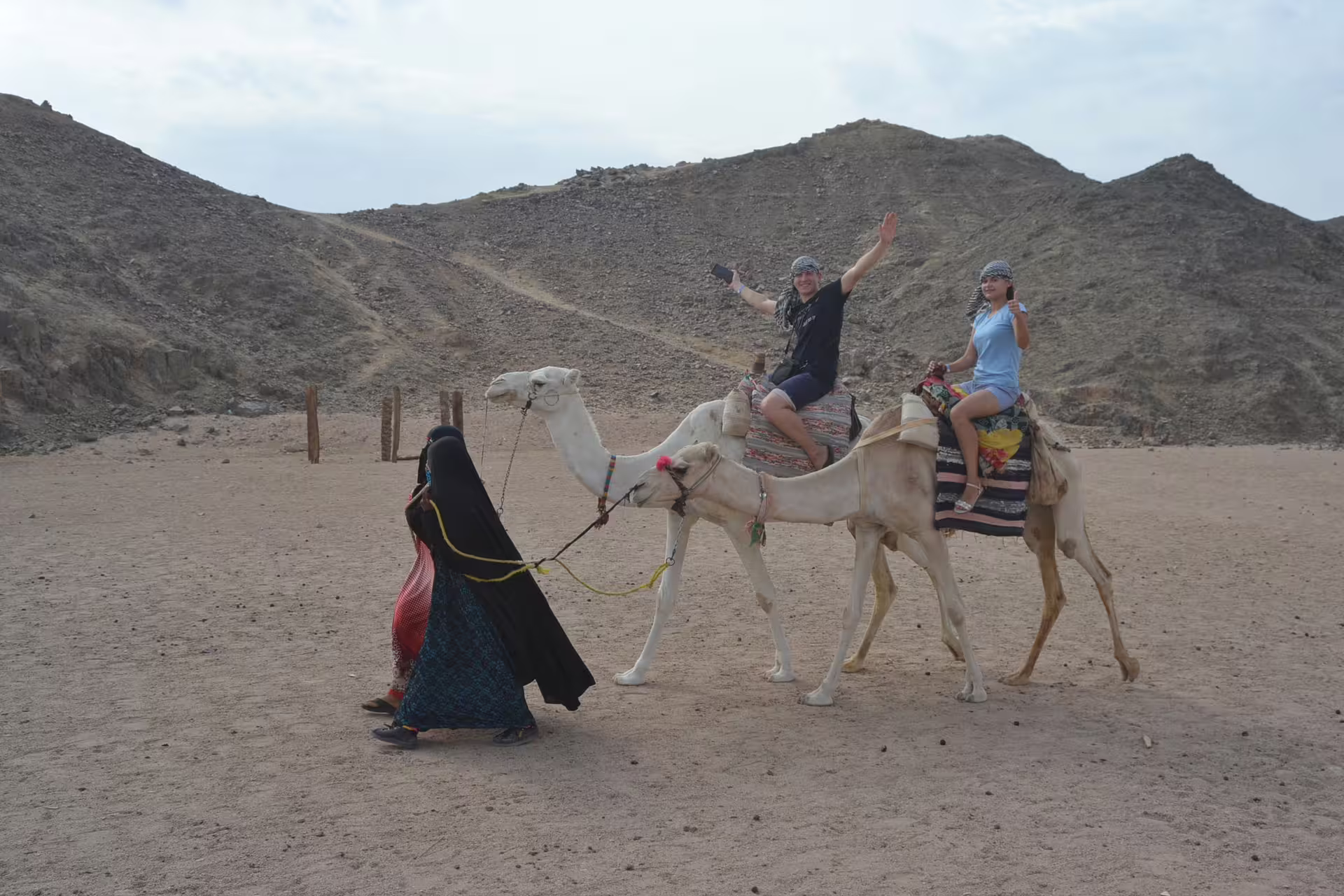 Couple on camel ride in Hurghada desert during Mega Safari, guided trek with rocky mountains in the background