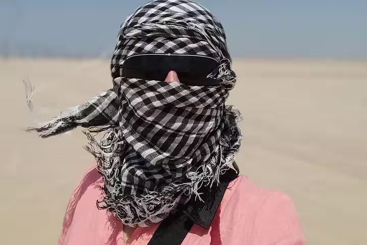 Quad biking across sandy desert with palm trees, sunset desert safari tour with camel ride and Bedouin dinner