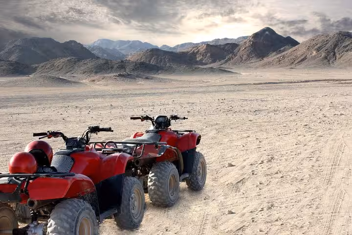 Red quad bikes parked in Hurghada desert with mountains, part of 6-hour jeep safari with BBQ dinner show