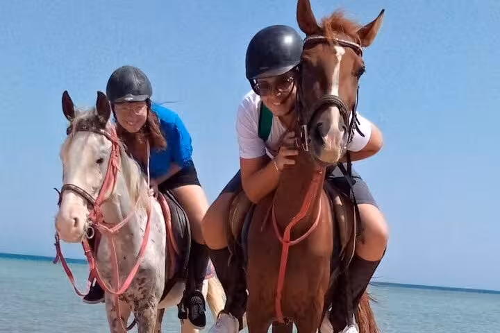 Couple leans forward on horses by the Red Sea, Hurghada desert and sea horse riding tour with beach swim option