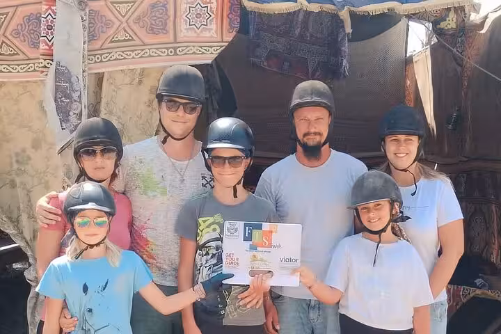 Family in riding helmets with guide at Bedouin camp stop on Hurghada desert and sea horse riding tour