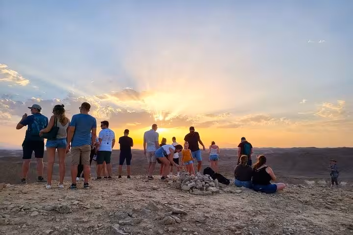 Group watching desert sunset near Hurghada on jeep safari, prelude to stargazing experience with ATV option