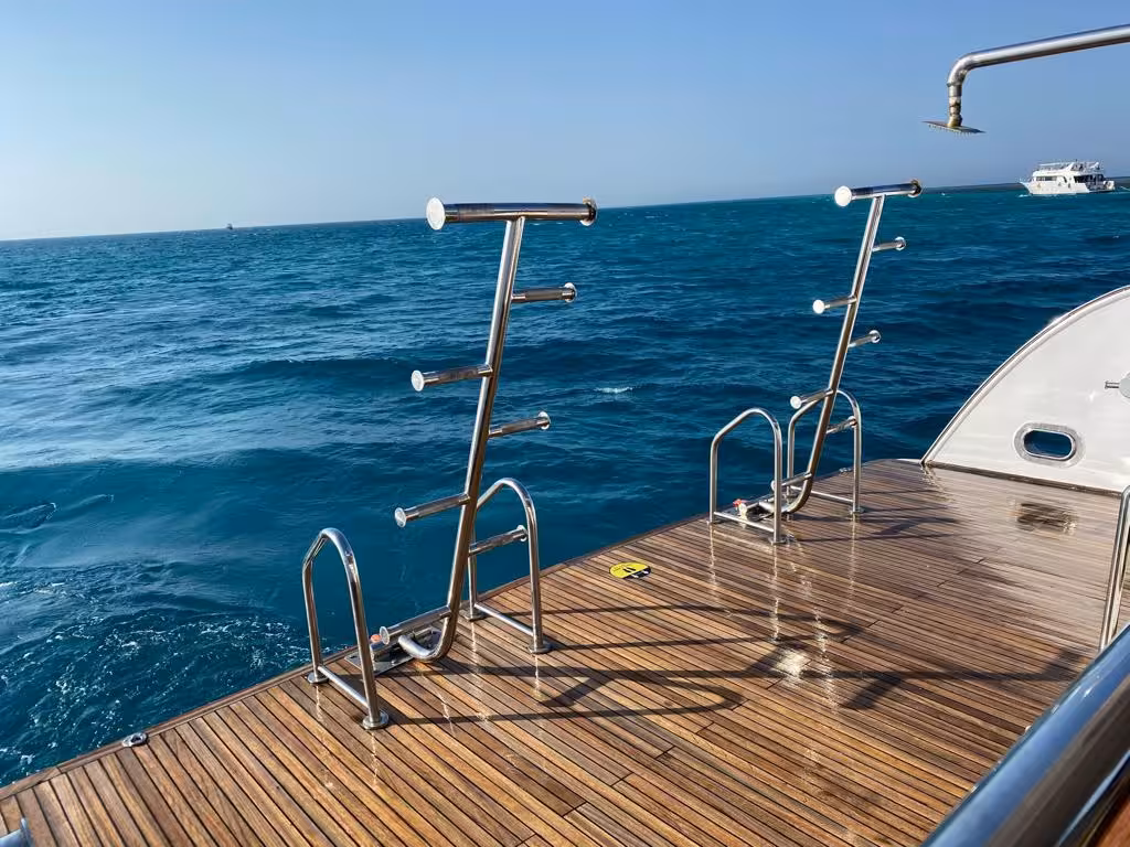 Wet teak swim platform with stainless steel ladders on a boat at Dolphin House, Hurghada, with turquoise sea