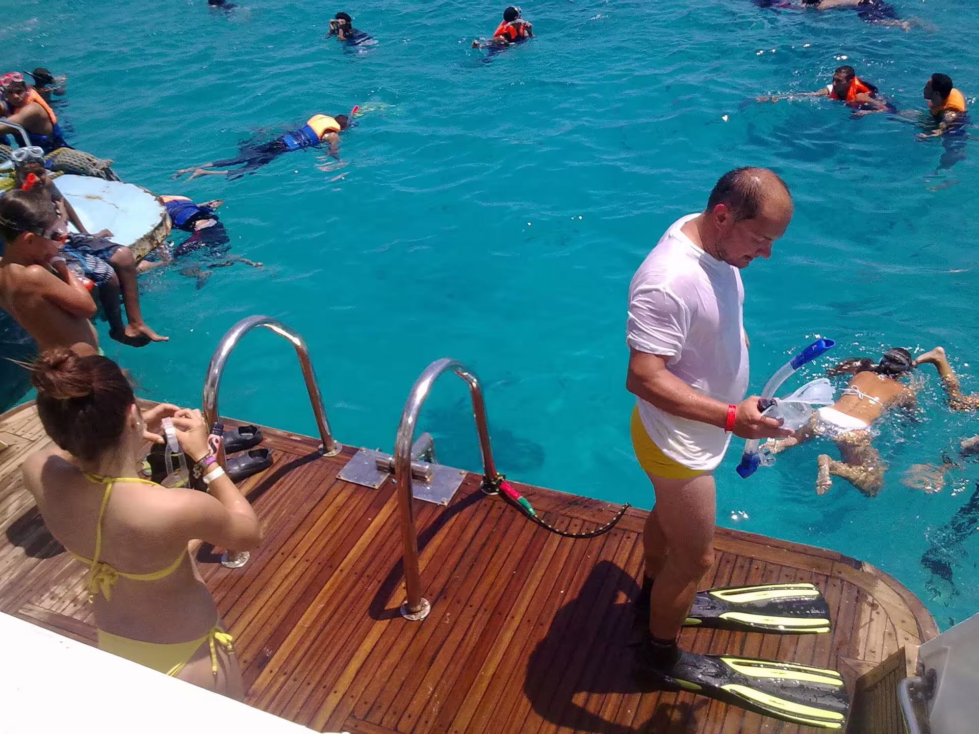 Tour guide with snorkel gear on boat deck as guests swim in turquoise Red Sea on Meet the Dolphins Hurghada