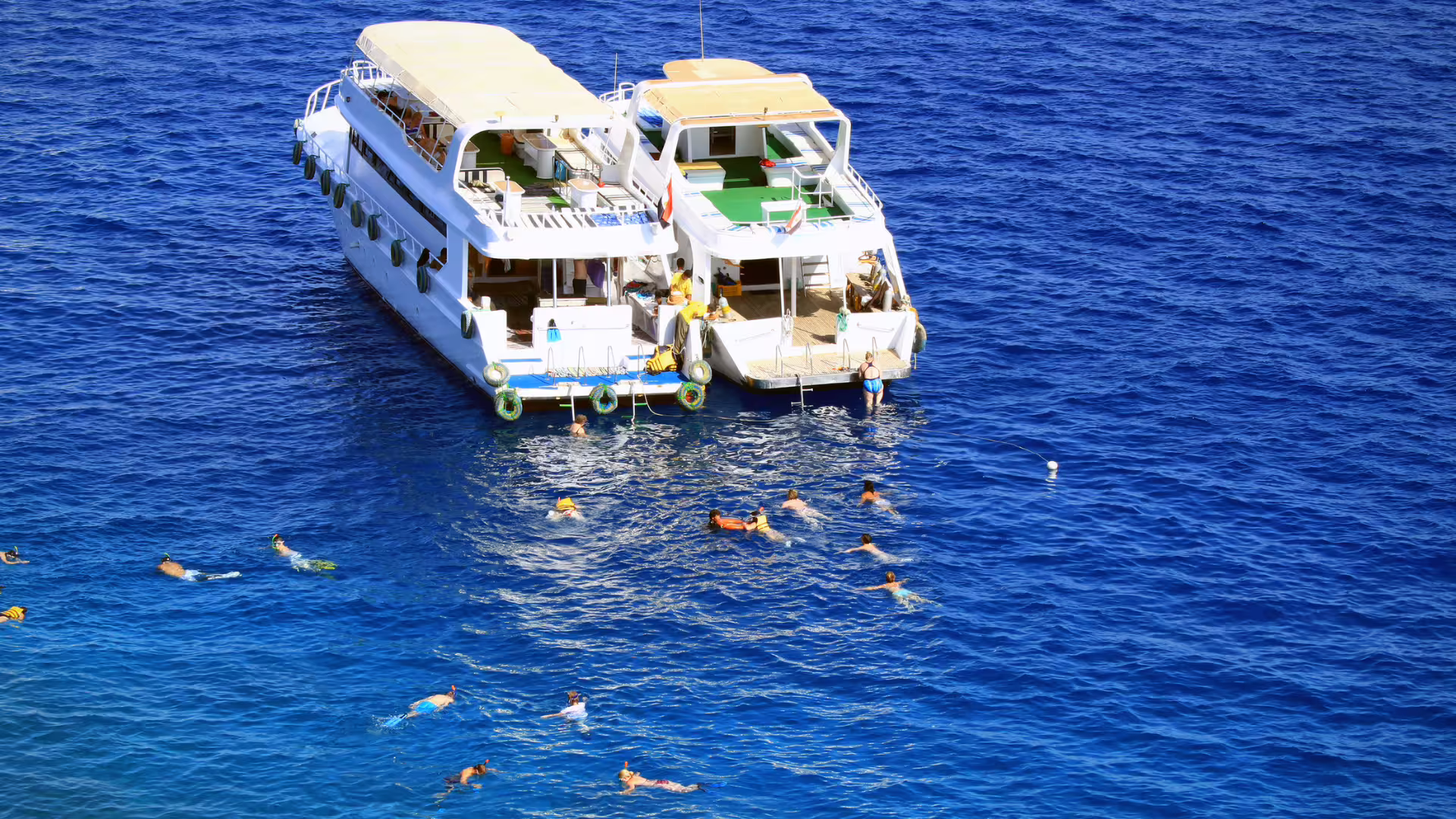Snorkel boat in Hurghada Red Sea with swimmers on Meet the Dolphins tour, crystal-blue water and reef stop
