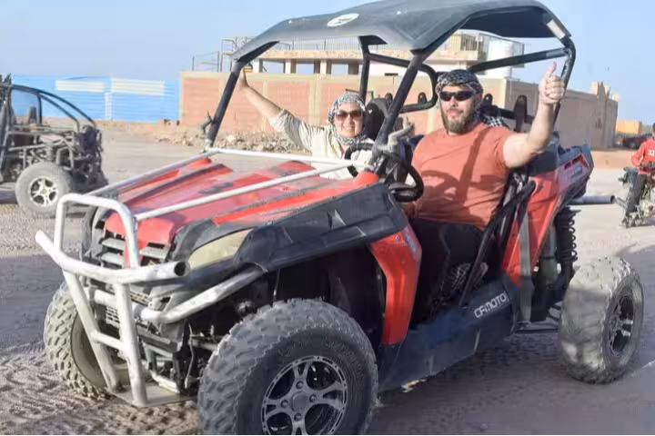 Couple in dune buggy on Hurghada desert super safari with headscarves, part of 7-day all-inclusive resort package