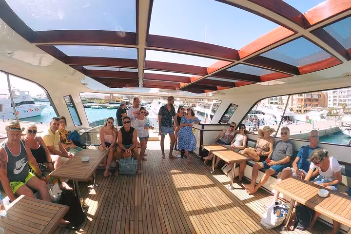 Guests on Hurghada to Eden Island boat cruise, spacious deck seating before snorkeling, water sports and lunch
