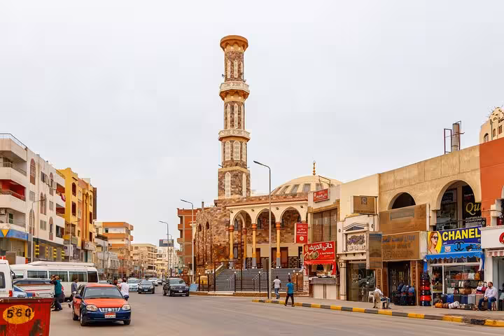 Hurghada city guided tour passing a mosque minaret and local shops on a bustling downtown street