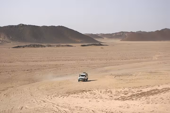 Jeep driving through wide Hurghada desert valley on 6-hour safari adventure, ending with BBQ dinner and show