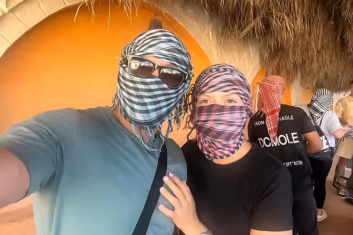 Couple wearing desert scarves at Bedouin camp on Hurghada Jeep desert safari with BBQ dinner and live show