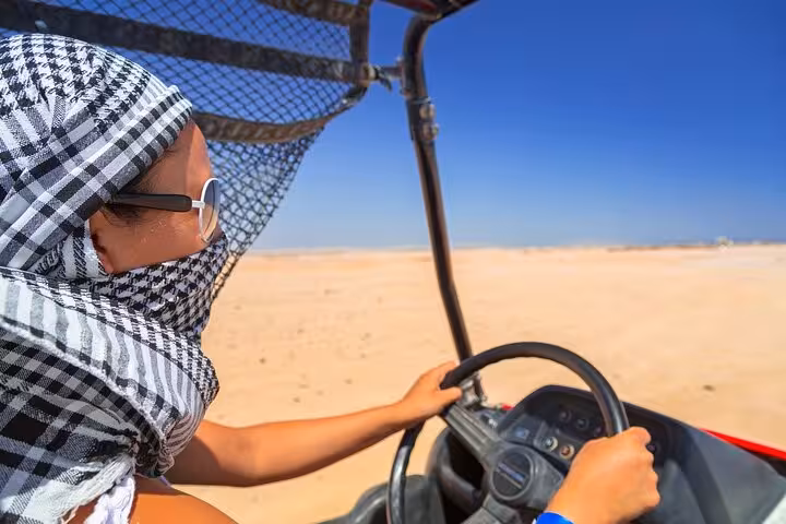 Traveler driving desert buggy in Hurghada wearing keffiyeh, on 6-hour jeep desert safari with BBQ dinner show