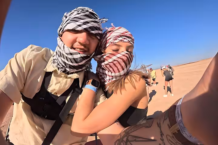 Couple in headscarves taking a selfie on Hurghada jeep desert safari, before BBQ dinner and evening show