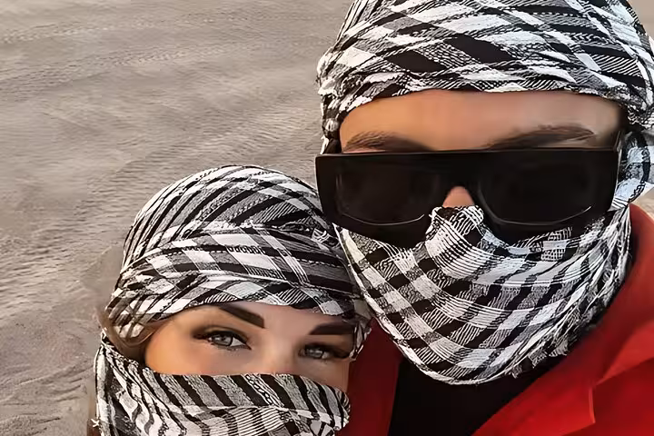 Couple wearing keffiyeh and sunglasses in Hurghada desert during 6-hour jeep safari with BBQ dinner and show
